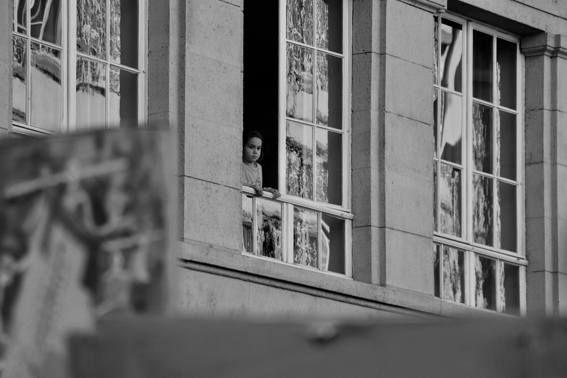 child leaning out of window of institutional building