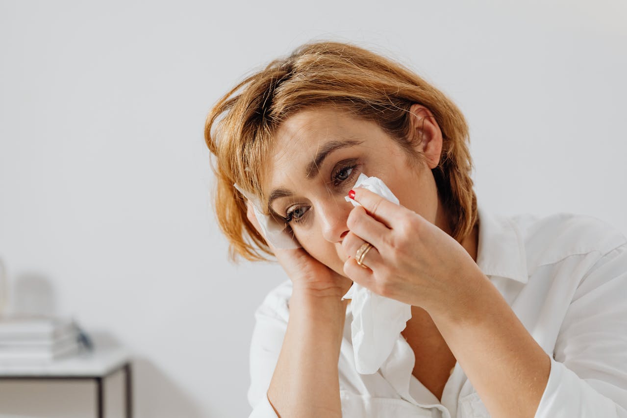 woman in white shirt wiping away tears